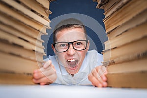 School boy in glasses sitting between two piles of books and loo