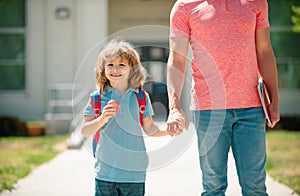 School boy going to school with father. Kid elementary student carrying backpacks holding parent fathers hand walking up
