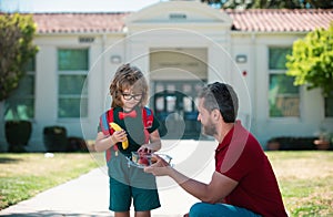 School boy going to school with father. Little schoolboy eating tasty lunch outdoors. School lunch for child.