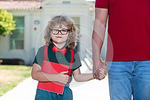 School boy going to school with father. Teachers day. Portrait of happy nerd pupil holding teachers hand.