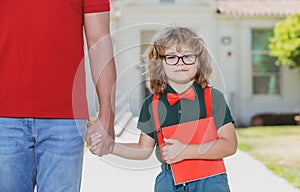 School boy going to school with father. Teachers day. Portrait of happy nerd pupil holding teachers hand.