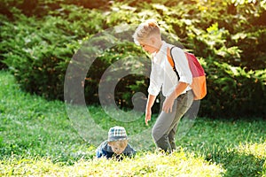 School boy helps to stand up his friend. Children help and support each other. Happy brothers outdoors