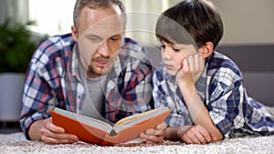 School boy listening to dad reading exciting adventure book, love to literature