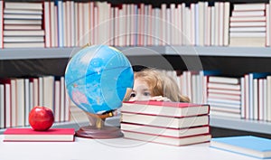School boy looking at globe in library, geography lesson. School child student learning in class, study english language