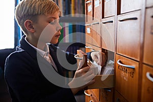 school boy looking for his card in the library, opening lockers