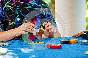 School boy playing board game with colorful bricks. Happy child build tower of wooden blocks, developing fine motor