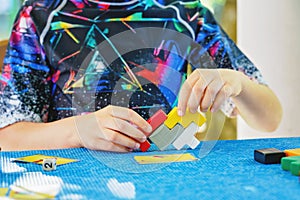 School boy playing board game with colorful bricks. Happy child build tower of wooden blocks, developing fine motor