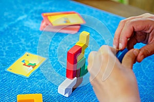 School boy playing board game with colorful bricks. Happy child build tower of wooden blocks, developing fine motor