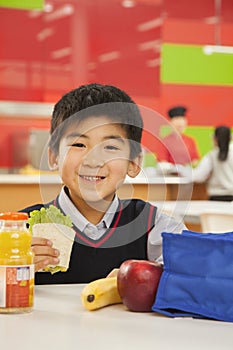School boy portrait eating lunch in school cafeteria