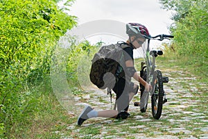 School boy in the protective helmet fix bike in the Park