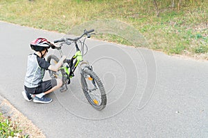 School boy in the protective helmet fix bike on the road