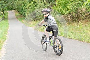 School boy in the protective helmet riding bike in the Park