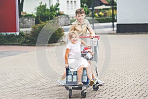 A School Boy Pushes the Cart While a Preschool Girl Happily Sits Inside, as They Enjoy a Fun Family Shopping Trip. Happy