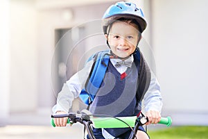 School boy in safety helmet riding bike with backpack