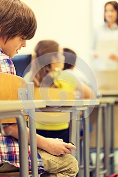 School boy with smartphone on lesson at classroom