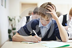School boy struggling to finish test in class.