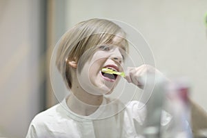 School boy with stylish haircut brushing his teeth