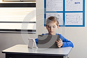 In school, boy using tablet for studying math in classroom