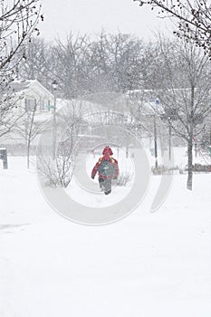 School boy walking under snow storm