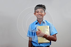 A school boy wearing uniform holds note books in hand