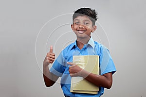 A school boy wearing uniform holds note books in hand