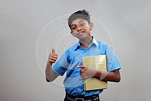 A school boy wearing uniform holds note books in hand