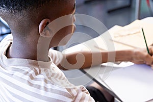 In school, boy writing in notebook at desk, focusing on assignment