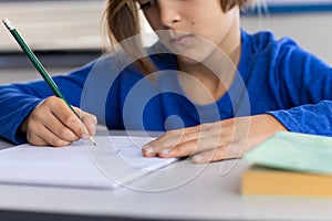 In school, boy writing in notebook, focusing on classroom assignment