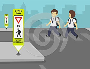 School boys crossing the street on crosswalk. Close-up of a crosswalk sign. Pedestrian crossing and a central island.