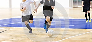 School boys on the indoor football tournament game. Football futsal players, ball, futsal floor. Indoor soccer sports hall