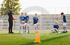 School Boys on Soccer Pitch. Young Coach Talking to Football Players During Training Session