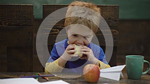 School break. Hungry kid eating apple in classroom. Schoolboy having an apple during his lunch break. Healthy food for