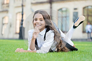 School break for rest. Happy smiling pupil. Girl cute kid laying green grass. Happy kid relaxing outdoors. Girl school