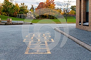 School building and school yard with hopscotch and playground for elementary students in evening in fall season