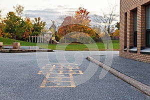 School building and school yard with hopscotch and playground for elementary students in evening in fall season