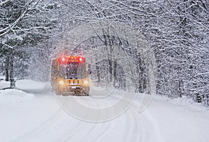 School Bus Travelling on a Snow Covered Rural Road with Stop Lights Flashing