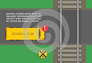 School buses must stop at railway crossings. Top view of a yellow school bus stopped at level crossing.