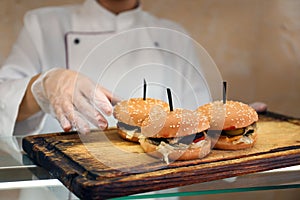 School canteen worker with burgers at serving line, closeup. Tasty food