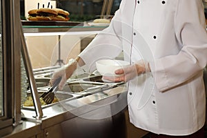 School canteen worker at serving line, closeup. Tasty food