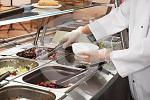 School canteen worker at serving line. Tasty food