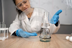 School chemistry classroom, teacher shows science experiment by setting spirit lamp with flask on the desk.