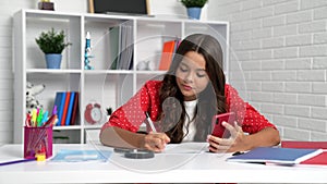 School child doing homework using smartphone at desk, mobile education