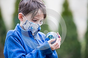 School child, holding small globe, looking sad at the world during Covid 19 pandemic