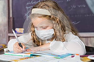 School child with protective masks against coronavirus at lesson in class room.girl writing in book. back to school