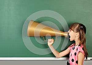 School child shouting magaphone near blank school blackboard, co