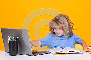 School child using laptop computer. School and kids. Cute blonde child with a book learning. Knowledge day.