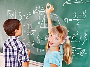 School child writting on blackboard.