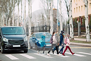 School children cross the road in medical masks. Children go to school.