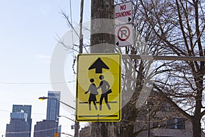 School children crossing traffic sign on a utility pole