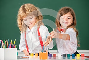 School children drawing a colorful pictures with pencil crayons in classroom. Portrait of cute pupils enjoying art and